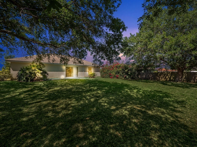 view of front facade featuring stucco siding, a yard, and fence