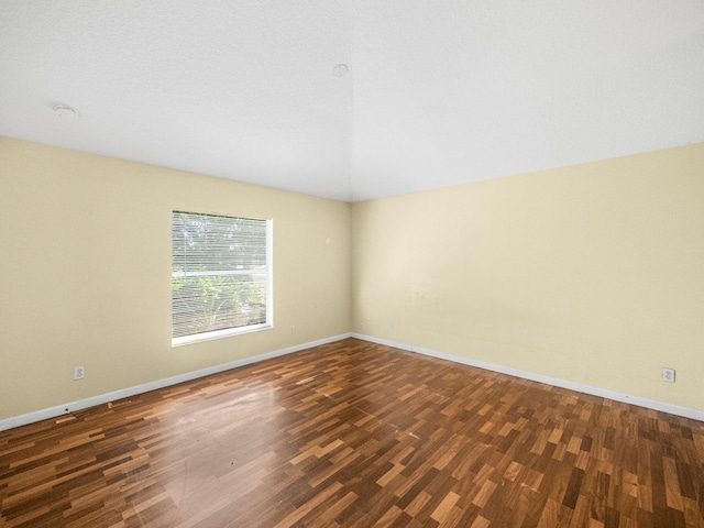 spare room with vaulted ceiling, baseboards, and wood finished floors