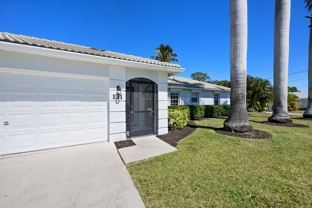 131 NE Naranja Ave, Port Saint Lucie, FL 34983 - doorway to property with stucco siding, a lawn, concrete driveway, a garage, and a tiled roof