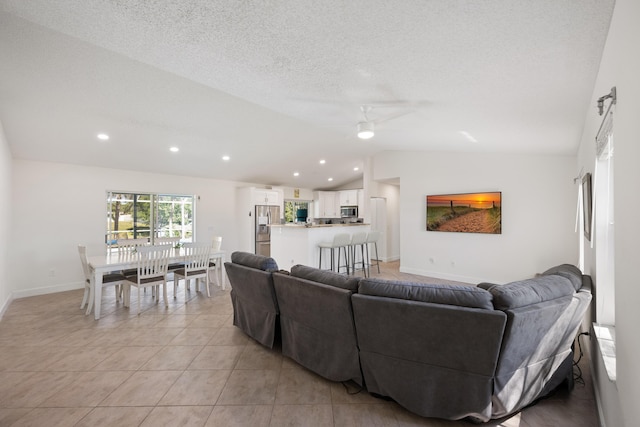 131 NE Naranja Ave, Port Saint Lucie, FL 34983 - living area with a ceiling fan, a textured ceiling, light tile patterned flooring, baseboards, and vaulted ceiling