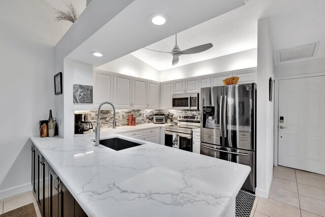 kitchen with ceiling fan, decorative backsplash, appliances with stainless steel finishes, a peninsula, and a sink