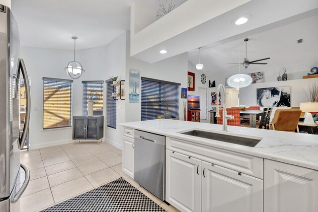 kitchen featuring a ceiling fan, a sink, stainless steel appliances, white cabinets, and decorative light fixtures