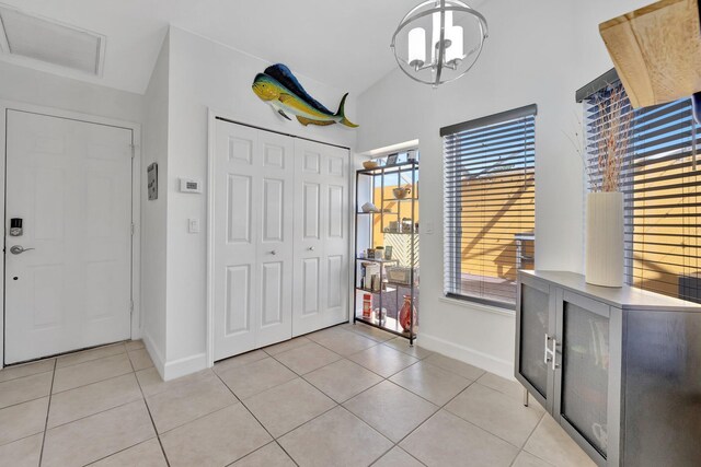 entrance foyer with visible vents, baseboards, an inviting chandelier, light tile patterned floors, and lofted ceiling
