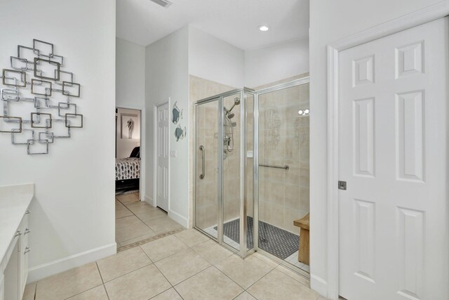 ensuite bathroom featuring a stall shower, connected bathroom, tile patterned flooring, baseboards, and vanity