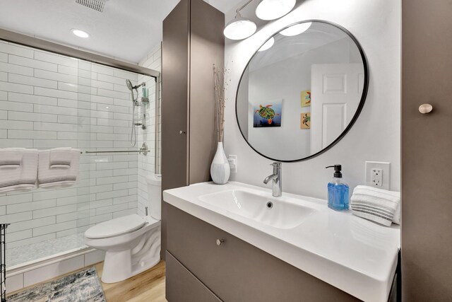 full bath featuring visible vents, toilet, a stall shower, wood finished floors, and vanity