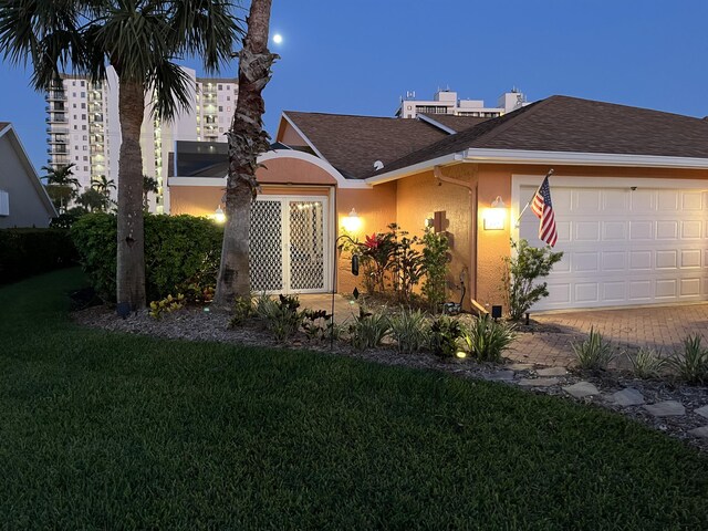 view of front of house with stucco siding, a front lawn, decorative driveway, roof with shingles, and a garage
