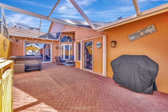 view of patio / terrace with grilling area, glass enclosure, and a hot tub