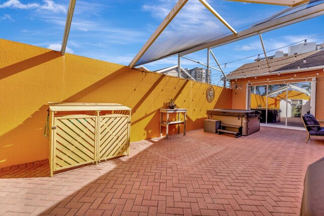 view of patio with a lanai and a hot tub