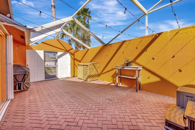 view of patio / terrace featuring glass enclosure, fence, and a gate