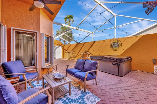 view of patio featuring glass enclosure, a hot tub, outdoor lounge area, and ceiling fan
