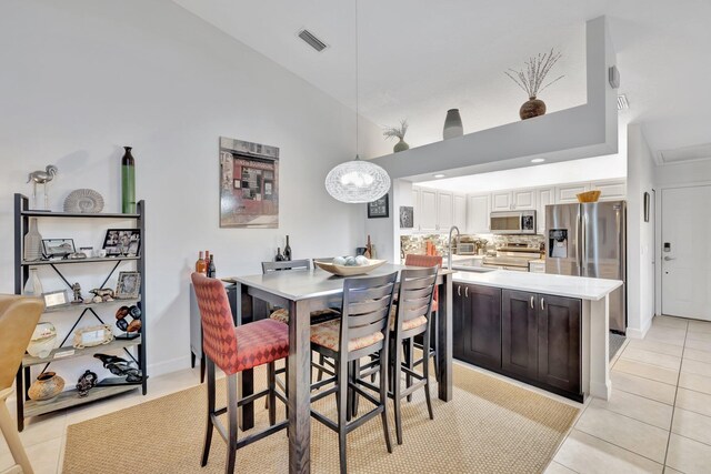 dining space featuring light tile patterned floors, visible vents, and high vaulted ceiling