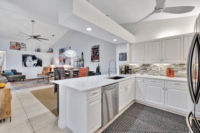 kitchen featuring vaulted ceiling, stainless steel dishwasher, freestanding refrigerator, a ceiling fan, and a sink