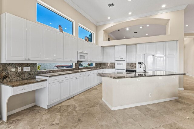 16137 Via Monteverde, Delray Beach, FL 33446 - kitchen with visible vents, crown molding, white appliances, dark stone counters, and a sink
