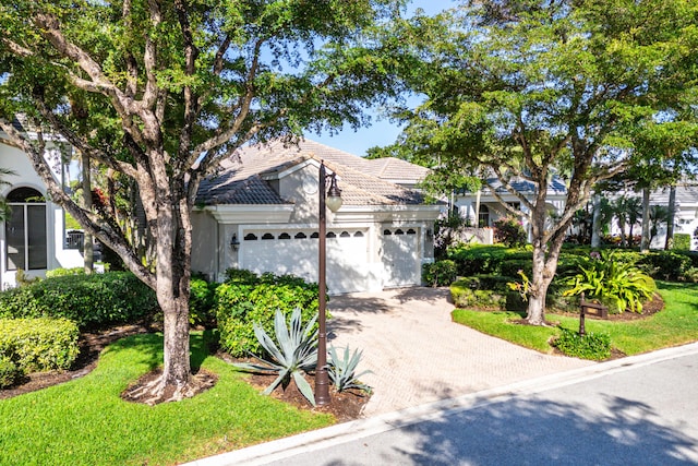16137 Via Monteverde, Delray Beach, FL 33446 - view of front of house with a front yard, stucco siding, an attached garage, a tiled roof, and decorative driveway