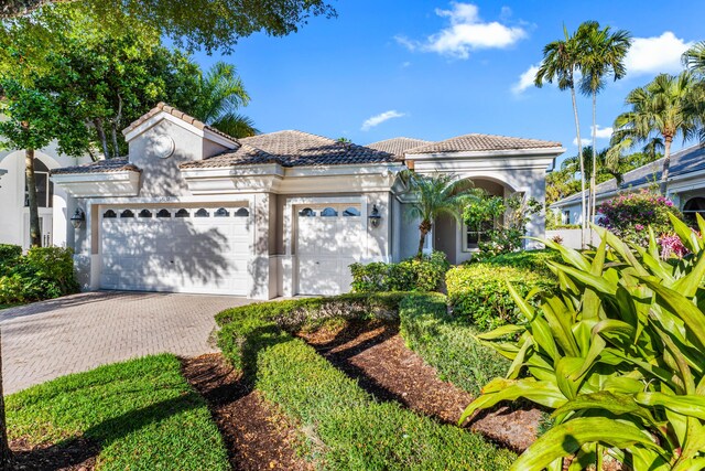 16137 Via Monteverde, Delray Beach, FL 33446 - mediterranean / spanish-style home featuring stucco siding, an attached garage, a tile roof, and decorative driveway