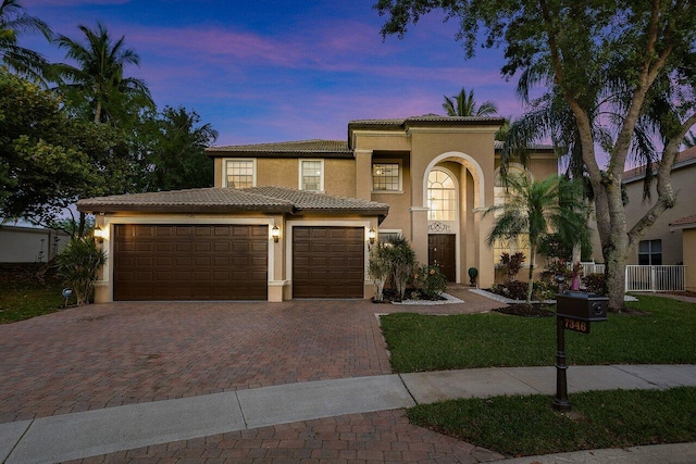 mediterranean / spanish-style home featuring stucco siding, an attached garage, decorative driveway, and a tiled roof
