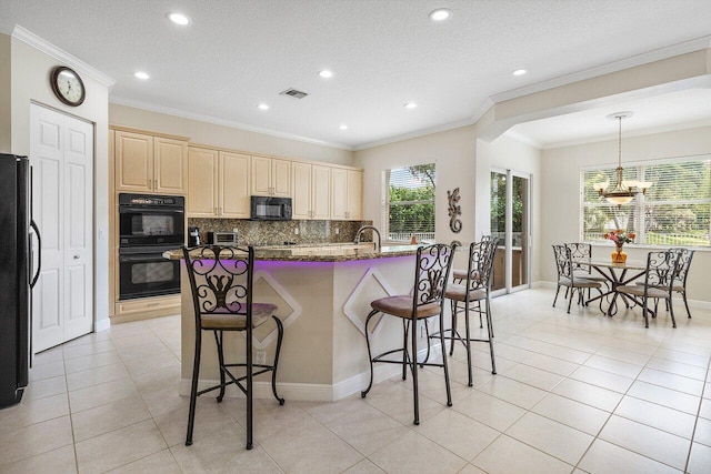 kitchen featuring visible vents, an inviting chandelier, a kitchen bar, decorative backsplash, and black appliances