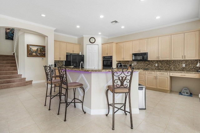 kitchen with visible vents, light brown cabinetry, decorative backsplash, and black appliances