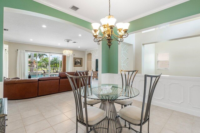 dining space featuring a wainscoted wall, visible vents, light tile patterned floors, arched walkways, and a chandelier