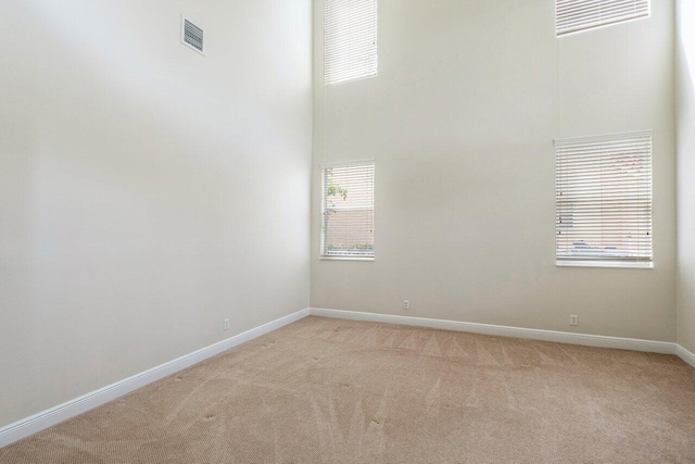 spare room with light colored carpet, baseboards, and visible vents