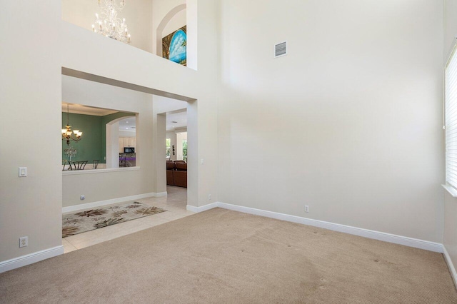 interior space featuring arched walkways, baseboards, visible vents, a notable chandelier, and a high ceiling