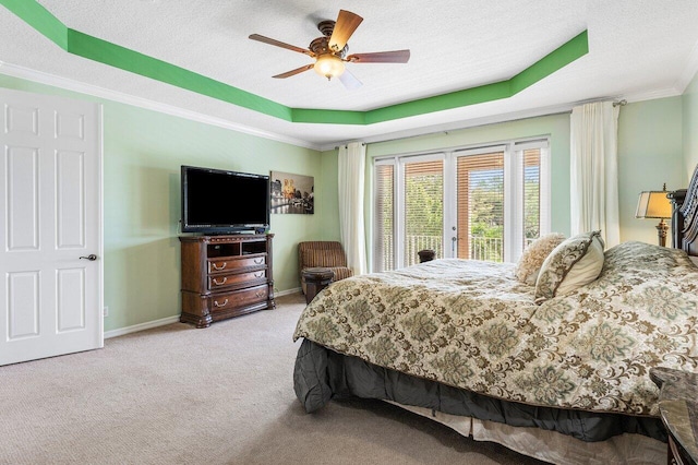 bedroom featuring a textured ceiling, baseboards, crown molding, carpet floors, and a raised ceiling