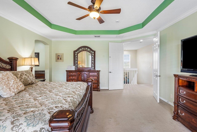 carpeted bedroom with a raised ceiling, visible vents, ornamental molding, arched walkways, and baseboards