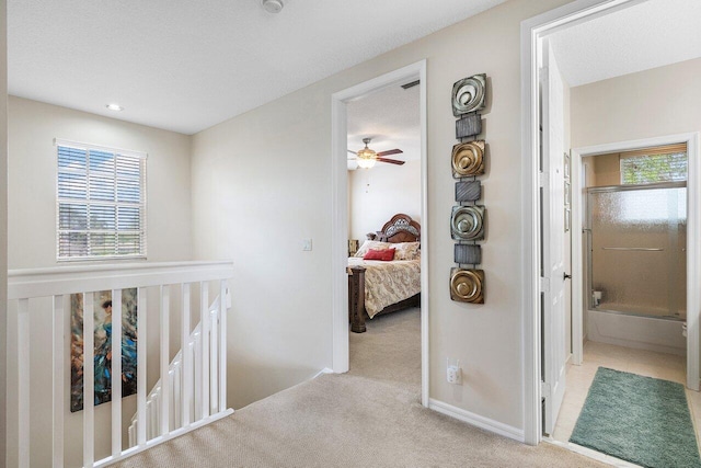 hallway featuring baseboards, a wealth of natural light, an upstairs landing, and carpet