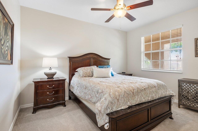 bedroom with light colored carpet, baseboards, and a ceiling fan