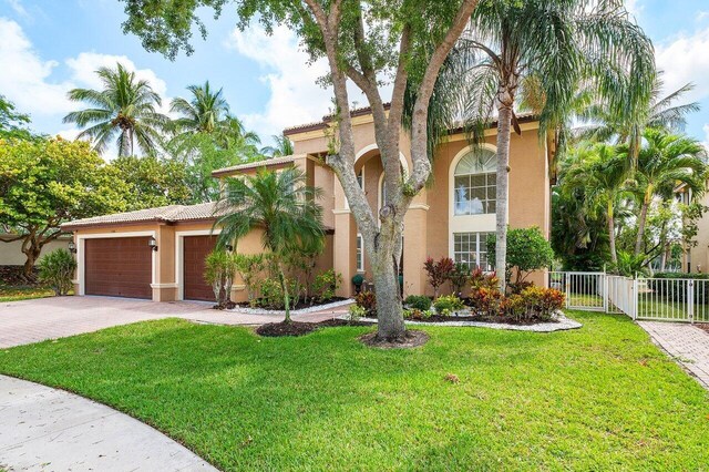 view of front facade featuring a tile roof, a front lawn, driveway, fence, and stucco siding