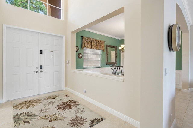 foyer entrance featuring baseboards, ornamental molding, a chandelier, and tile patterned floors