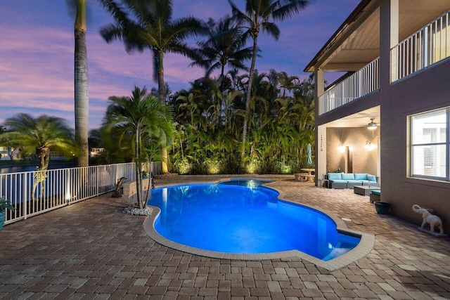 pool at dusk with a patio area, a fenced in pool, ceiling fan, and an outdoor hangout area