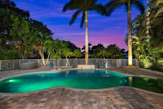 pool at dusk with a patio area, a fenced in pool, and fence