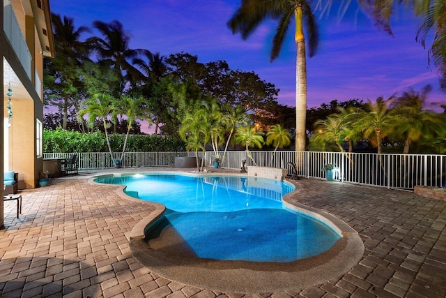 pool at dusk with a fenced in pool, a fenced backyard, and a patio