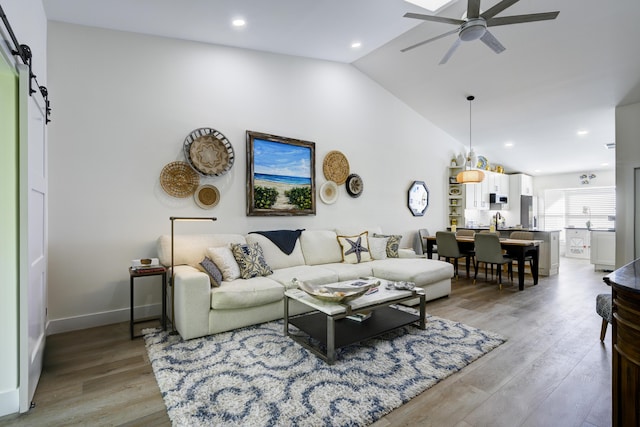 living area with recessed lighting, lofted ceiling, a ceiling fan, light wood-type flooring, and baseboards