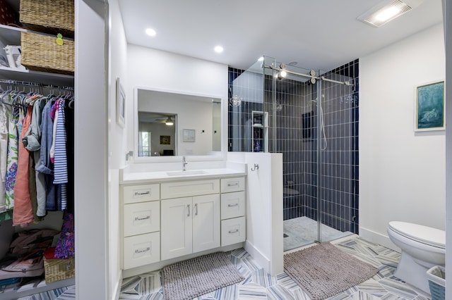 bathroom featuring a spacious closet, tiled shower, vanity, toilet, and recessed lighting