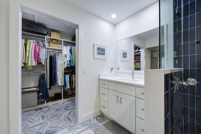 bathroom featuring tile patterned floors, a tile shower, a spacious closet, recessed lighting, and vanity