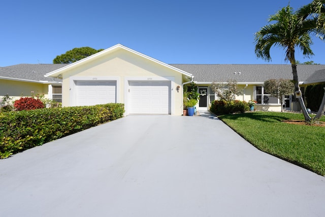 single story home featuring an attached garage, a front lawn, stucco siding, and driveway
