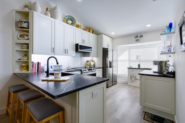 kitchen with open shelves, dark countertops, a sink, a peninsula, and appliances with stainless steel finishes