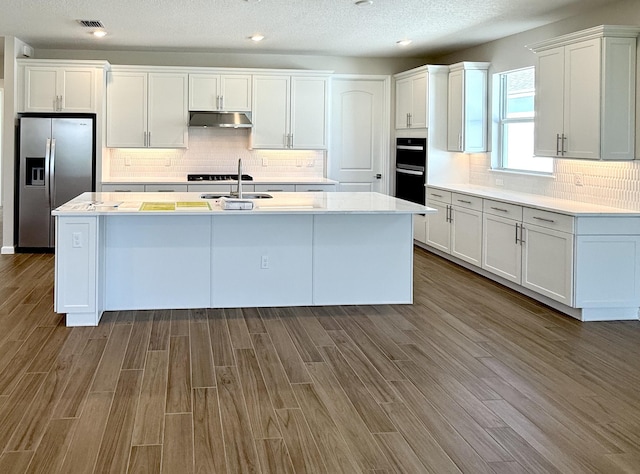 13532 Sw Vermillion Circle Palmary, Port Saint Lucie, FL 34987 - kitchen with stainless steel refrigerator with ice dispenser, under cabinet range hood, white cabinets, light countertops, and wood finished floors