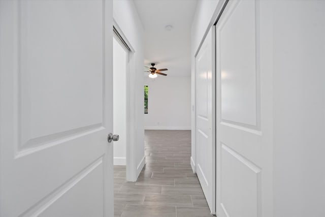 corridor featuring baseboards and light wood finished floors