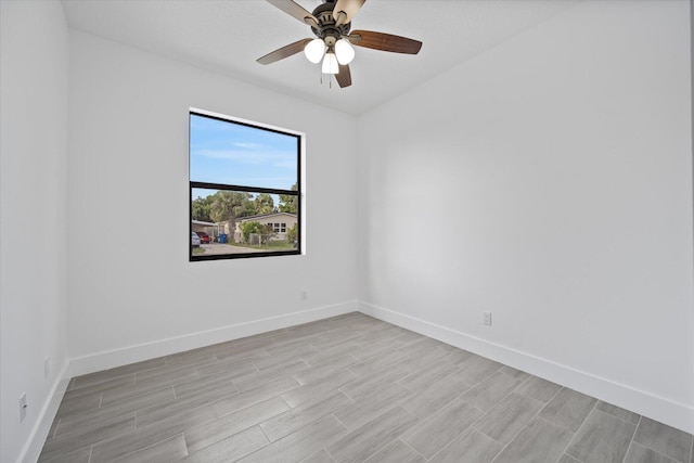 spare room with baseboards, a ceiling fan, and light wood-type flooring