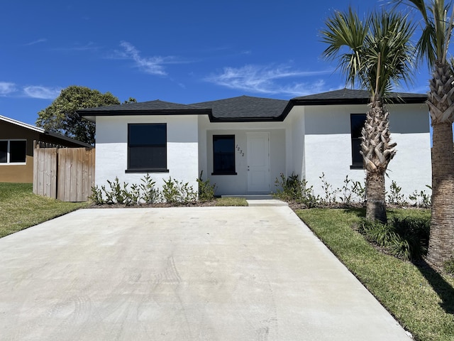 view of front of home with roof with shingles, stucco siding, and fence