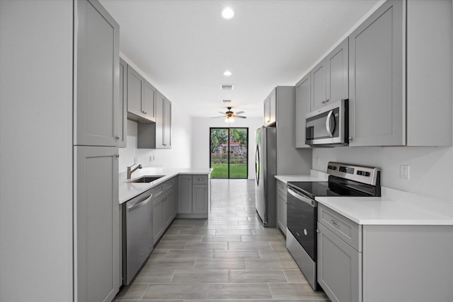 kitchen with a sink, gray cabinets, stainless steel appliances, and ceiling fan