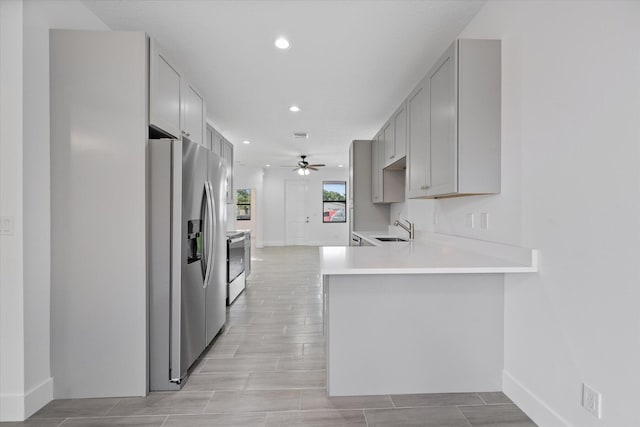 kitchen with a sink, stainless steel fridge with ice dispenser, range with electric cooktop, a ceiling fan, and gray cabinetry