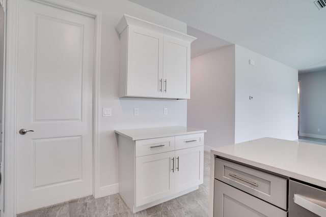 kitchen featuring white cabinetry, light countertops, baseboards, and visible vents