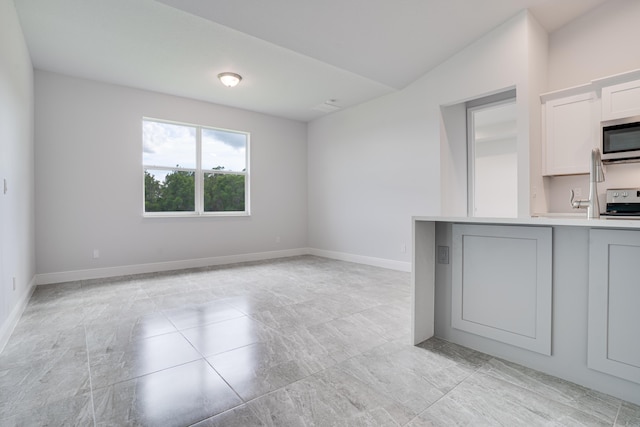 unfurnished living room featuring baseboards and vaulted ceiling