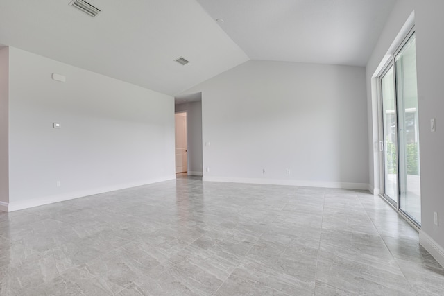 spare room featuring baseboards, visible vents, and vaulted ceiling