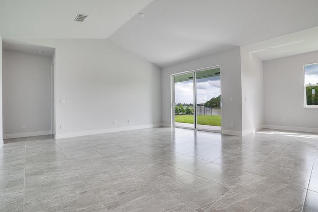 empty room featuring baseboards, visible vents, and lofted ceiling