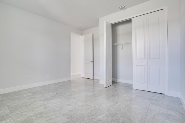 unfurnished bedroom with baseboards, visible vents, and a closet